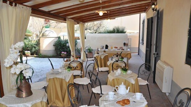 An outdoor patio with tables set for dining, featuring white tablecloths and metal chairs. - Il Mattino ha l'oro in bocca (Pisa)
