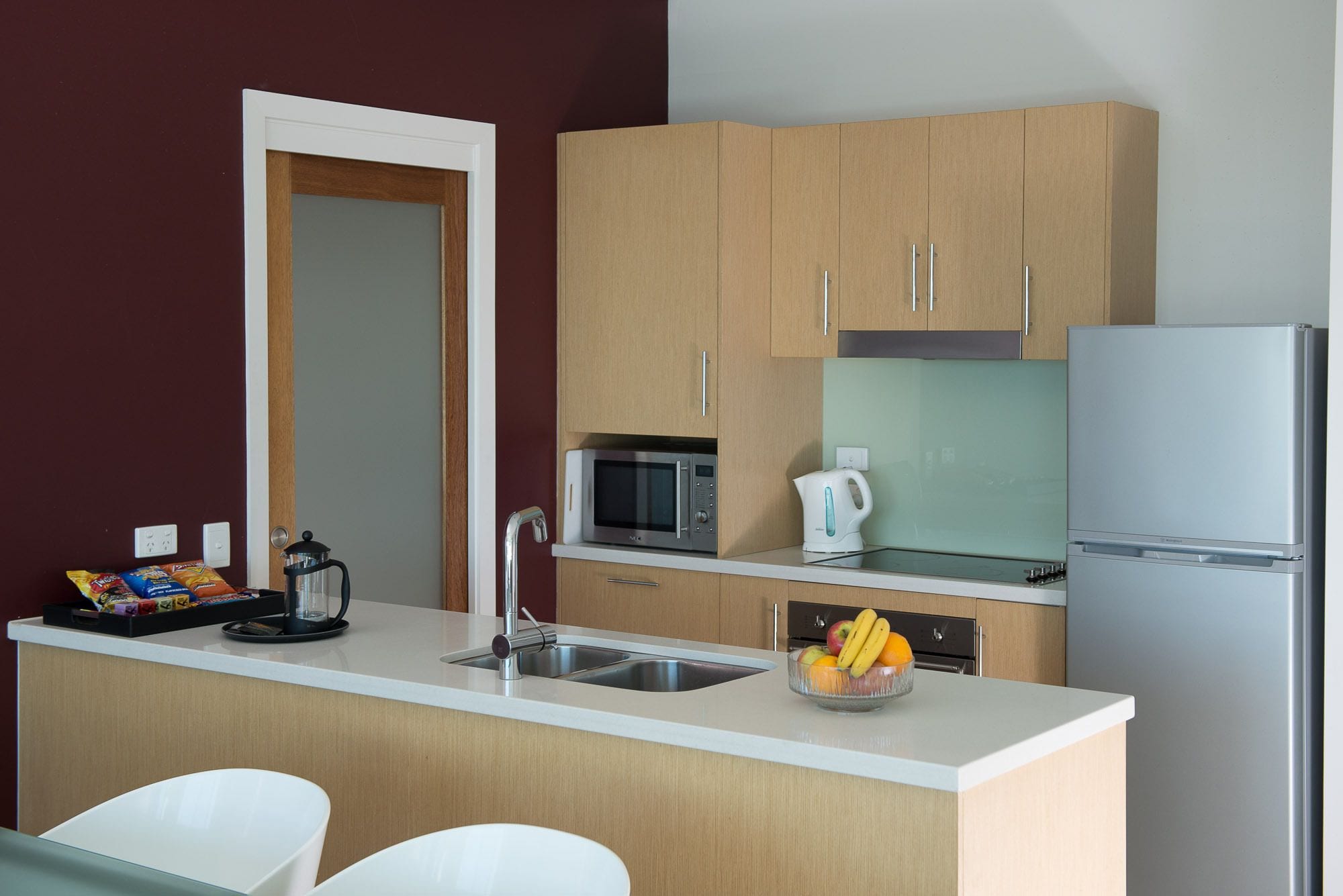 A compact kitchen with a microwave, kettle, and refrigerator.