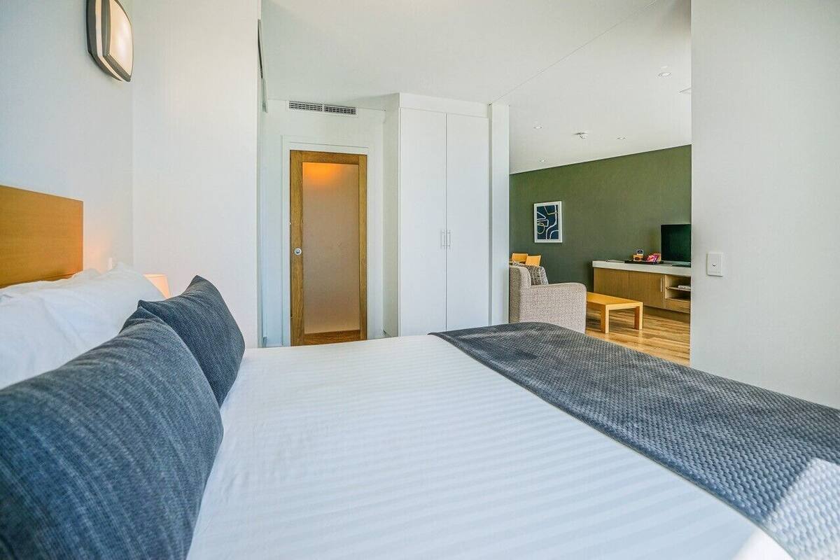 A hotel room with a bed, a desk, and a chair.