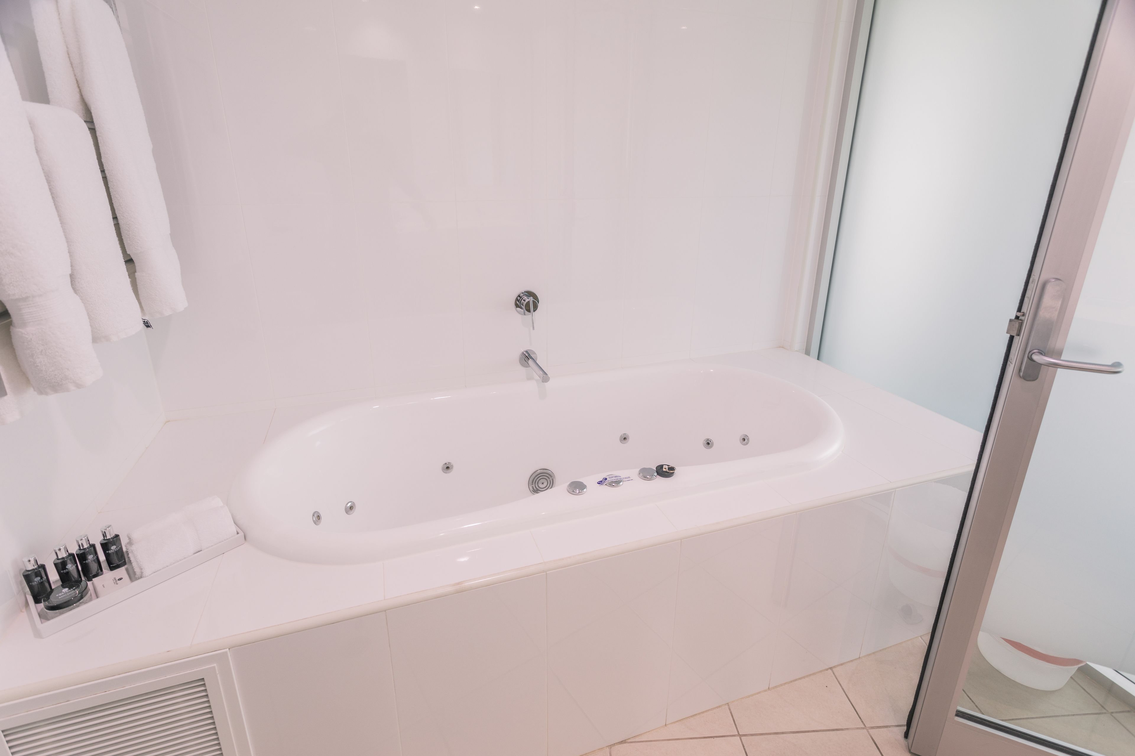 Un baño moderno con una bañera blanca, cabina de ducha de vidrio y lavamanos con tocador blanco.