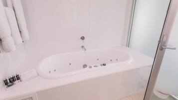 Un baño moderno con una bañera blanca, cabina de ducha de vidrio y lavamanos con tocador blanco.