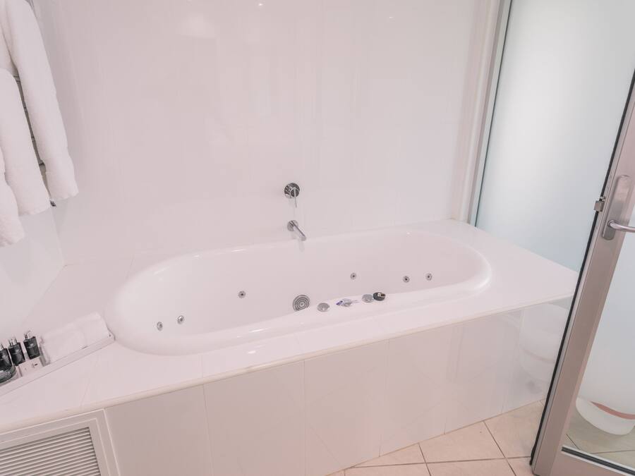 Un baño moderno con una bañera blanca, cabina de ducha de vidrio y lavamanos con tocador blanco.
