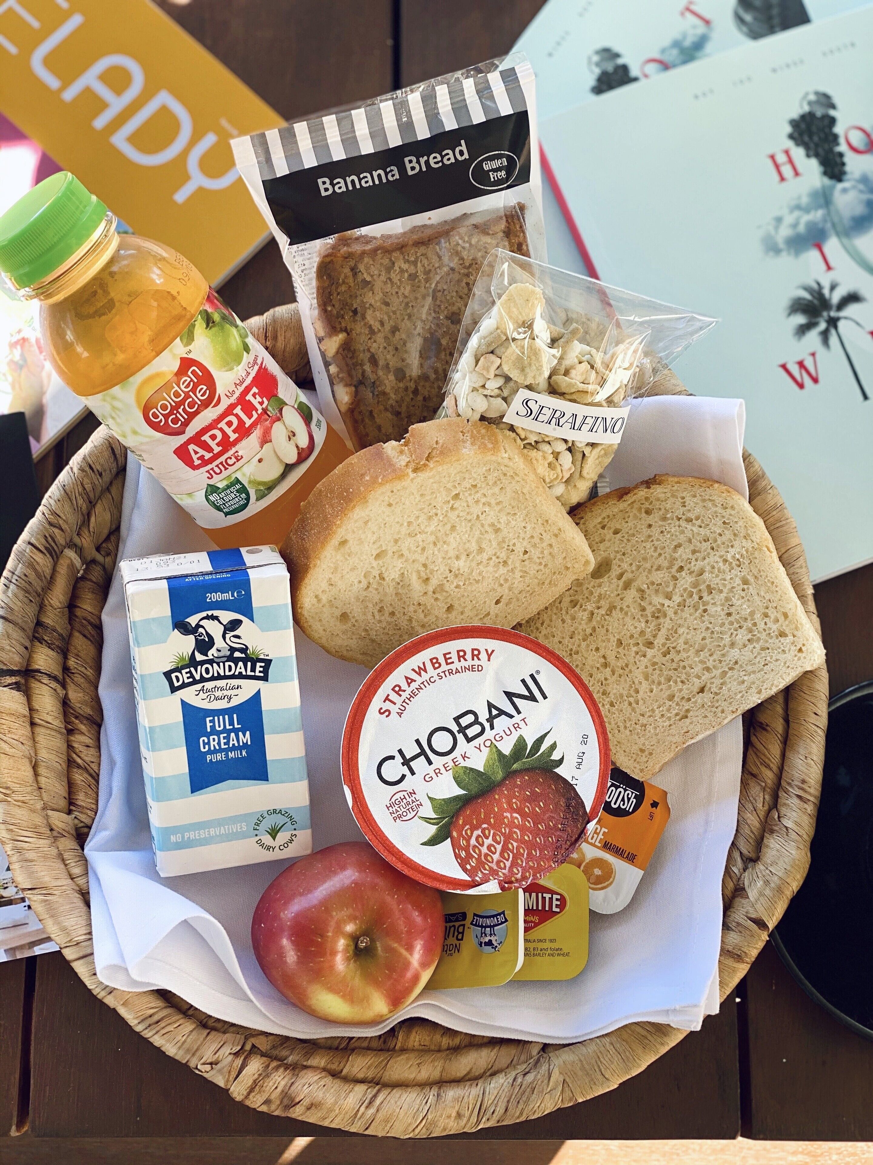 A basket containing various food items including bread, apple juice, yogurt, and a bottle of milk.