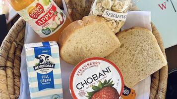 A basket containing various food items including bread, apple juice, yogurt, and a bottle of milk.