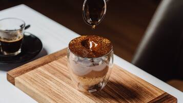 A layered dessert in a clear glass on a wooden board.
