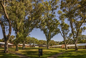 A hotel with multiple rooms, a grassy lawn, and trees.