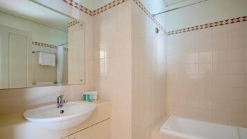 Ein Badezimmer mit Waschbecken, Spiegel und Badewanne.