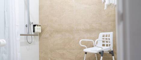 A bathroom with a shower, a white chair, and a towel rack.