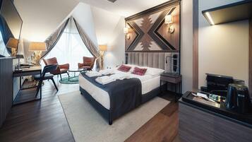 Une chambre d’hôtel moderne avec un grand lit, un bureau et une chaise. On trouve une machine à café et un téléviseur sur le bureau.