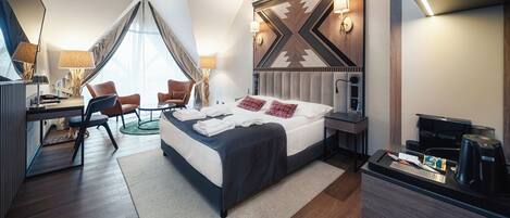 A modern hotel room with a large bed, a desk, and a chair. There is a coffee machine and a TV on the desk.