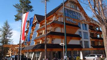 Un hotel de varios pisos con un diseño moderno, que presenta un llamativo letrero 'Rys Hotel'.