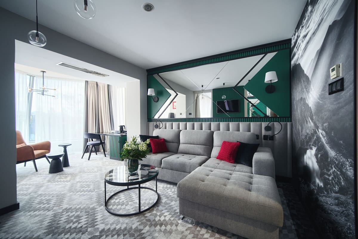 A modern living room with a grey sectional sofa, a glass coffee table, and a dining area with a table and chairs.