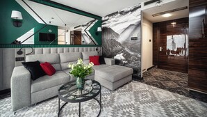 A modern living room with a grey sectional sofa, a glass coffee table, and a large mirror.