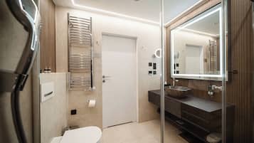 A modern bathroom with a toilet, a sink with a large basin, a mirror, and a towel rack.