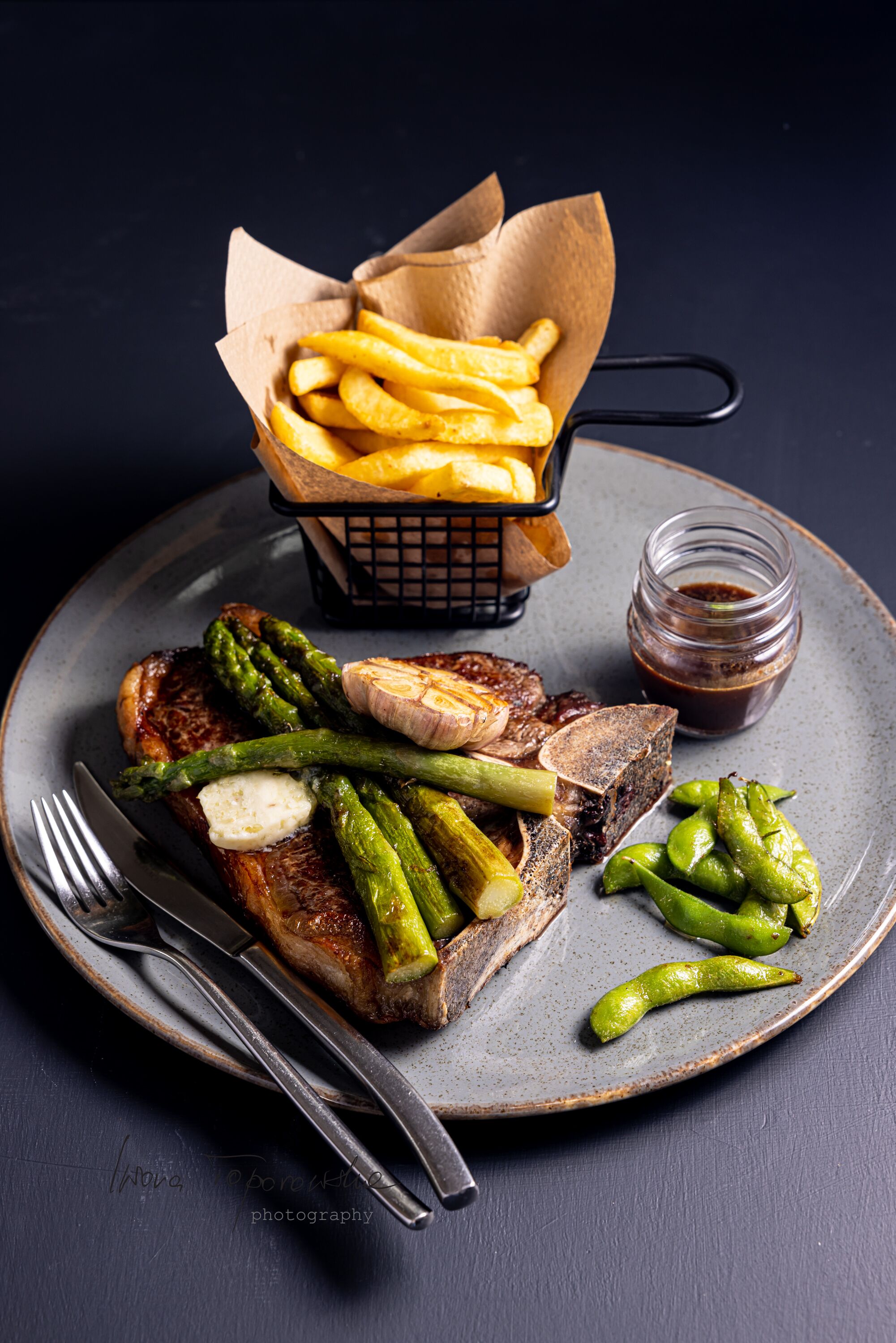 A plate with steak, asparagus, and French fries.