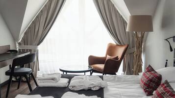 A hotel room with a bed, a chair, a desk, and a lamp.
