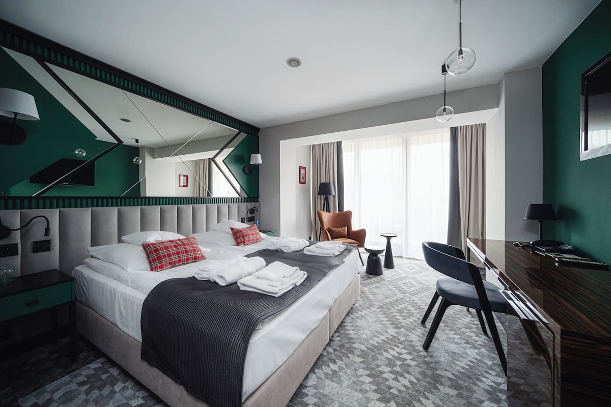 A modern hotel room with a large bed, a desk, and a chair.