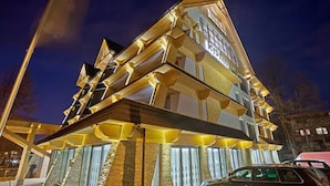 A multi-story building with a unique geometric facade, large windows, and a parked car in front.
