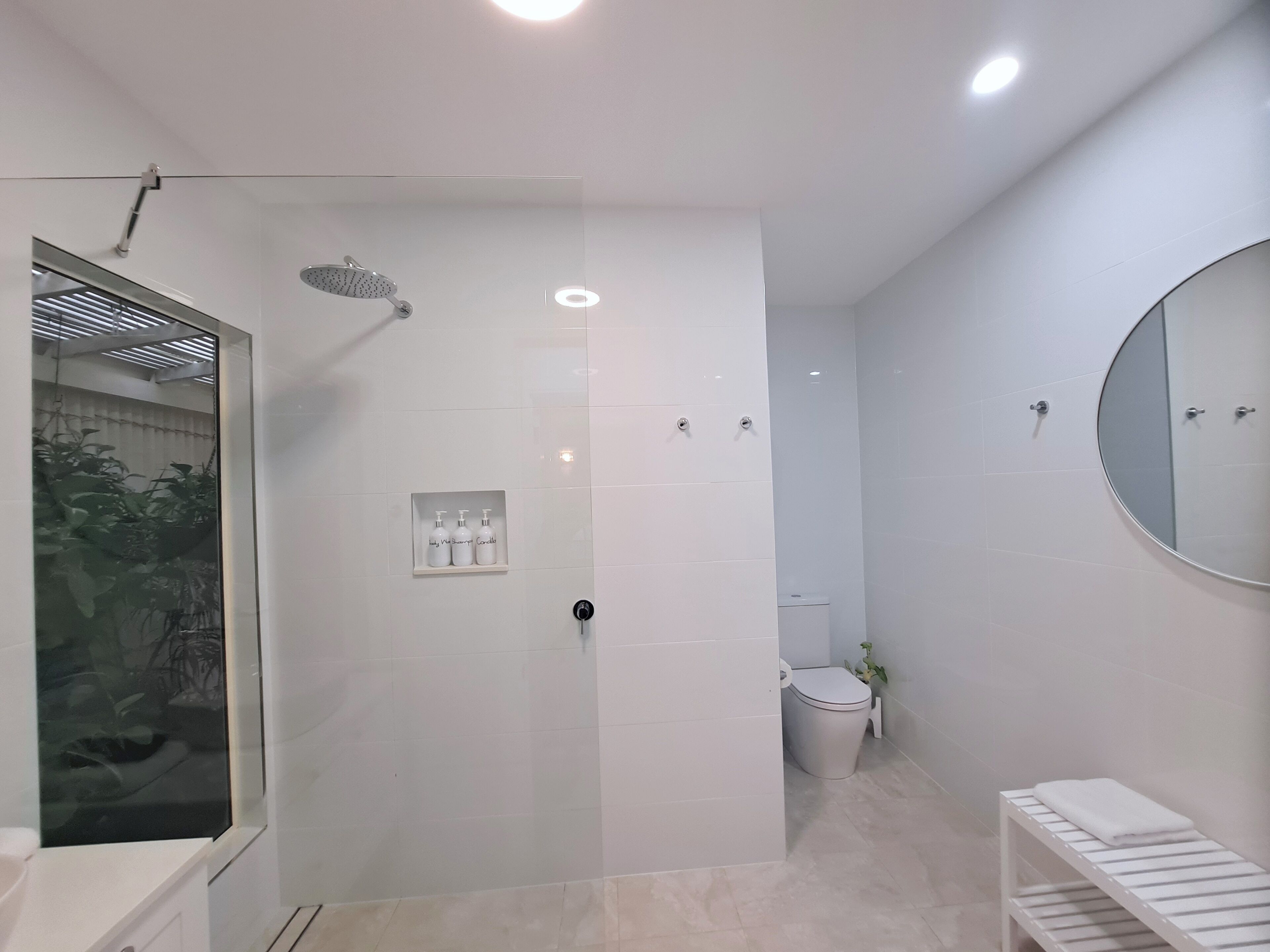 A modern bathroom with a glass shower enclosure, a toilet, and a sink with a towel rack.