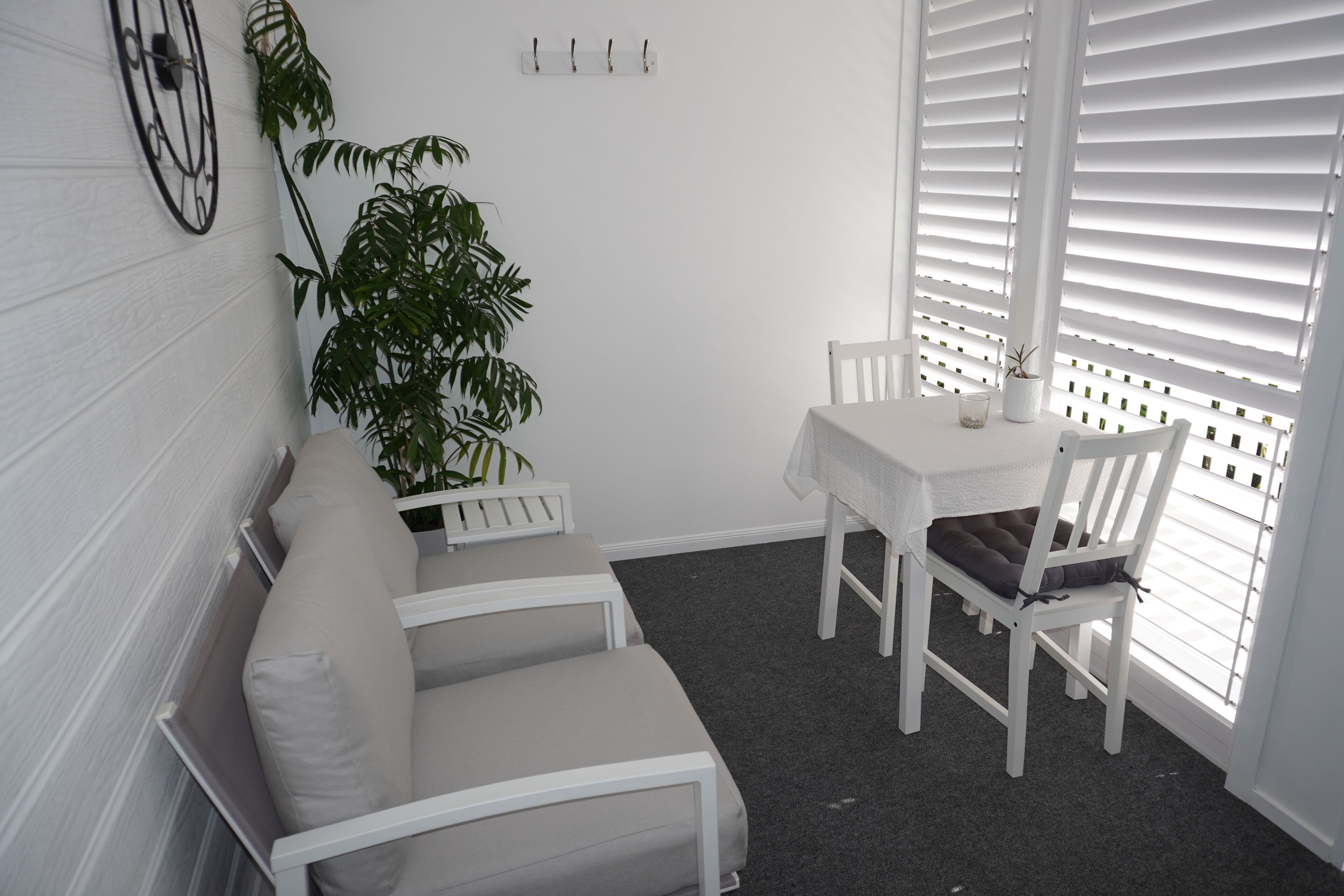 Una habitación blanca con un sofá, sillas, una mesa y una planta en maceta.