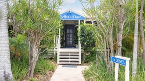 Edifici amb la façana que diu "Debbie's Place", una zona de recepció i un camí que hi convergeix, tot envoltat de vegetació tropical.