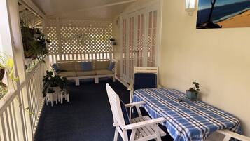 A cozy room with a bed, a small table, a chair, a bench, and a potted plant.