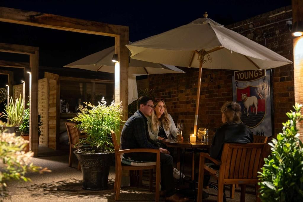 Een terras met tafels en stoelen, potplanten en een banner aan de muur.