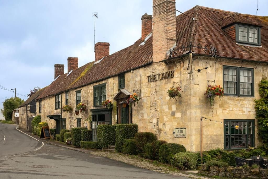 Een traditioneel stenen gebouw met een bord waarop 'THE LAMB' staat en een bordje dat 'A30 SALISBURY' aangeeft.