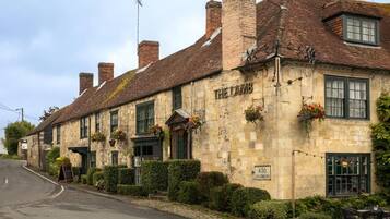 Een traditioneel stenen gebouw met een bord waarop 'THE LAMB' staat en een bordje dat 'A30 SALISBURY' aangeeft.