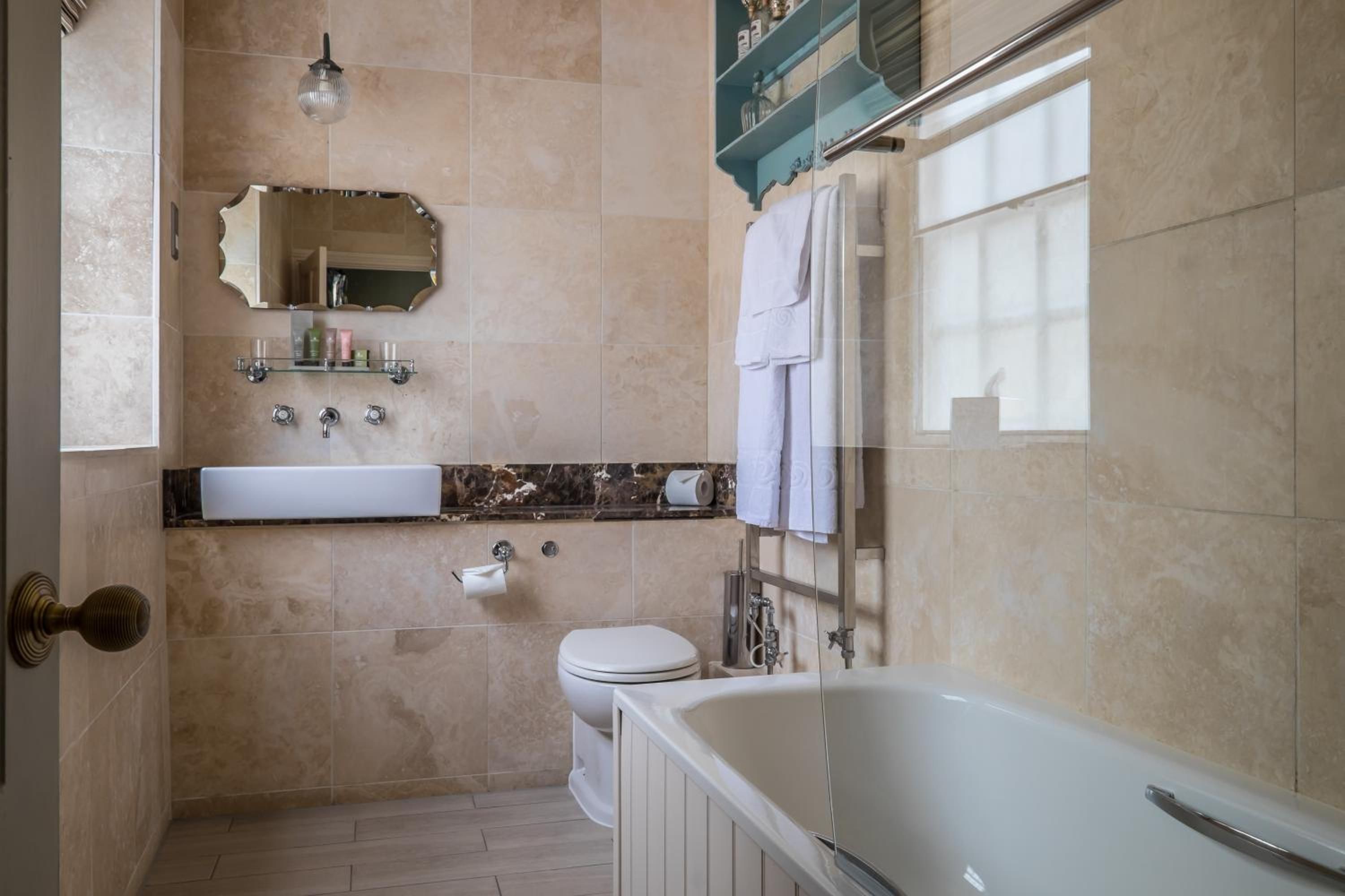 Een badkamer met een bad, toilet, wastafel en een spiegel.
