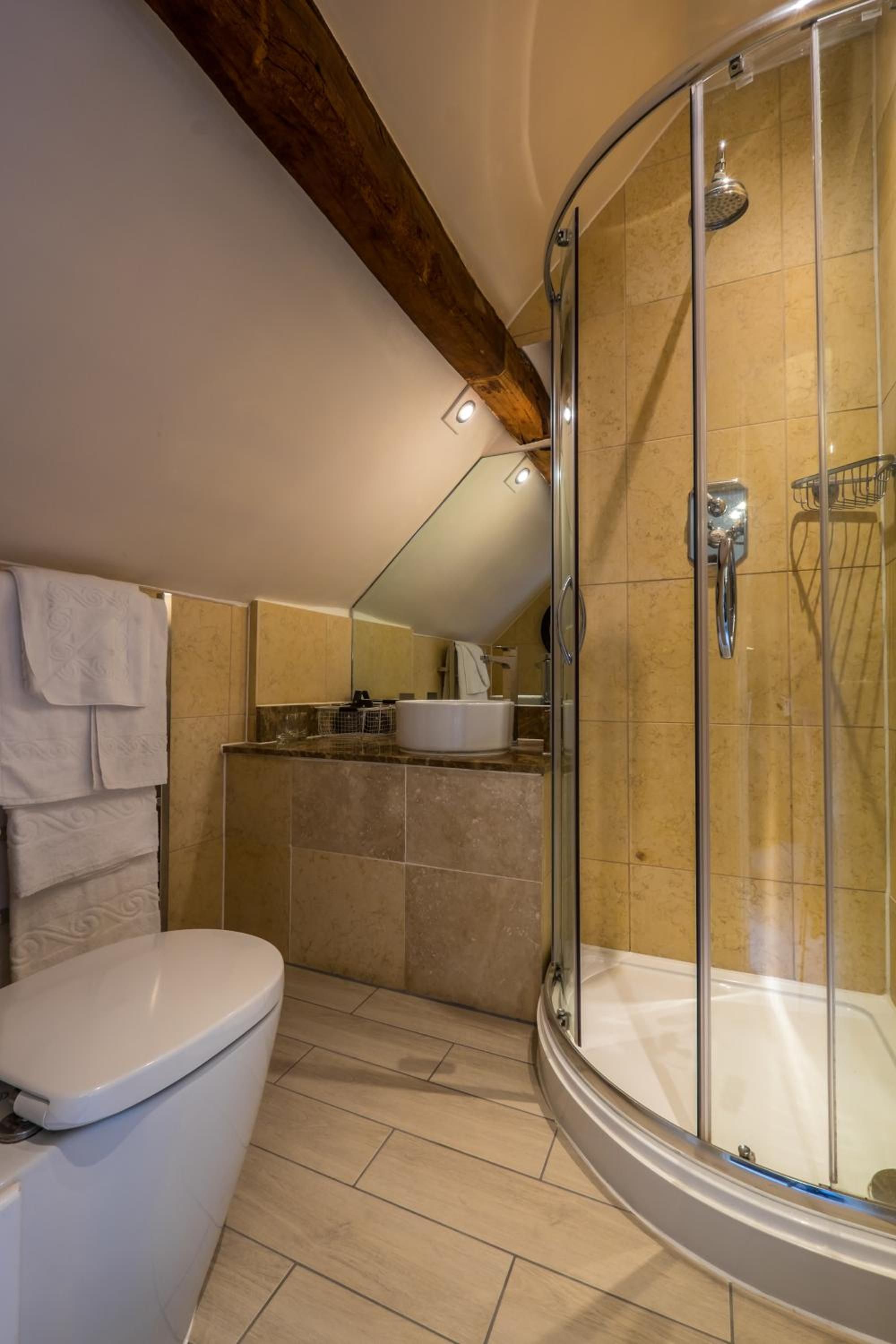 A modern bathroom with a glass-enclosed shower, a toilet, and a sink area.