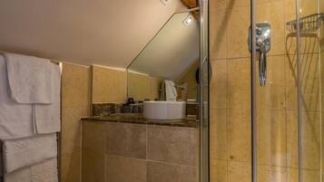 A modern bathroom with a glass-enclosed shower, a toilet, and a sink area.