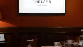 Interior de un restaurante con un cartel que dice "THE LAMB Pub & Rooms" sobre una mesa de comedor dispuesta con platos, vasos y copas.