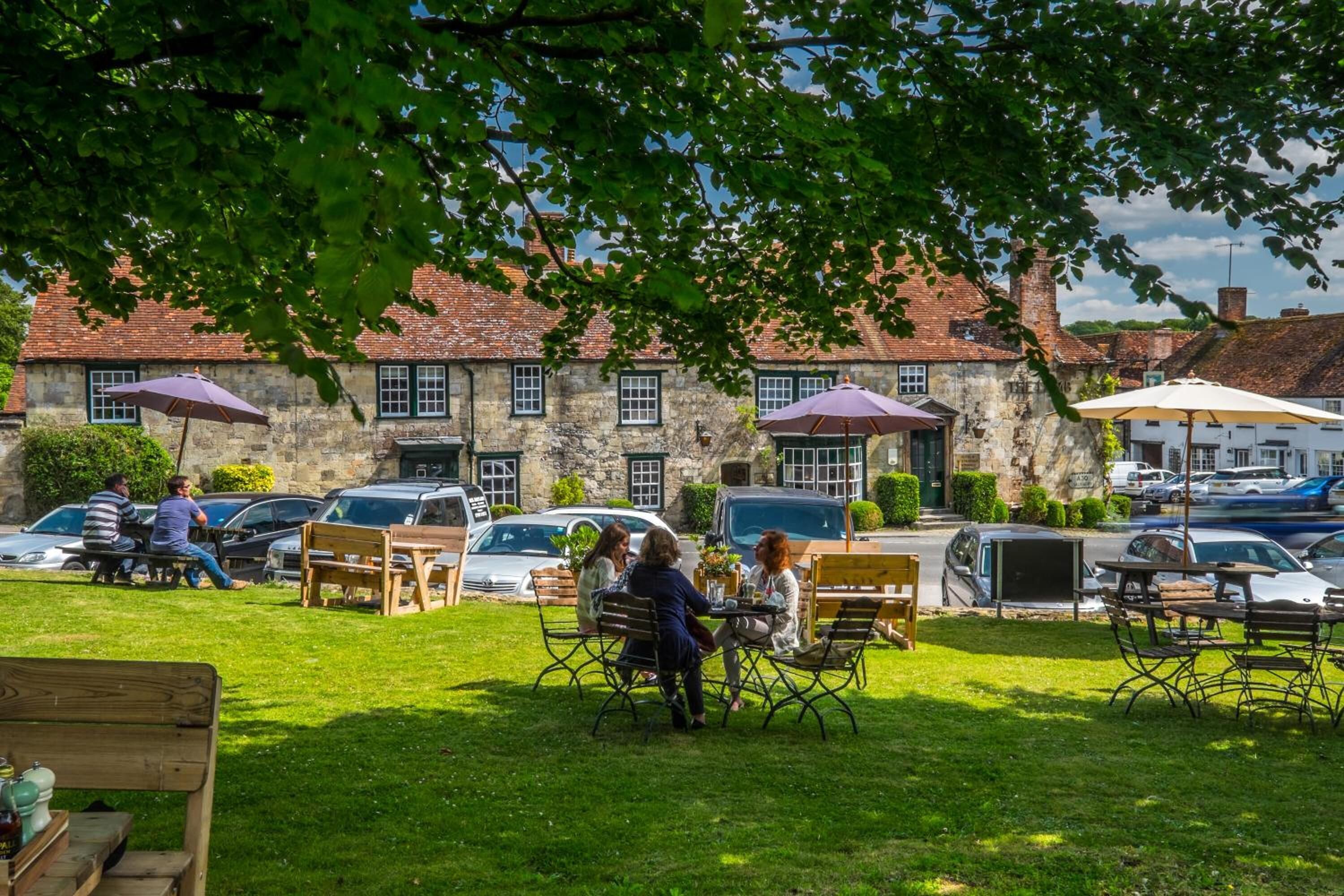 An outdoor seating area with tables and chairs, surrounded by stone buildings with red roofs.