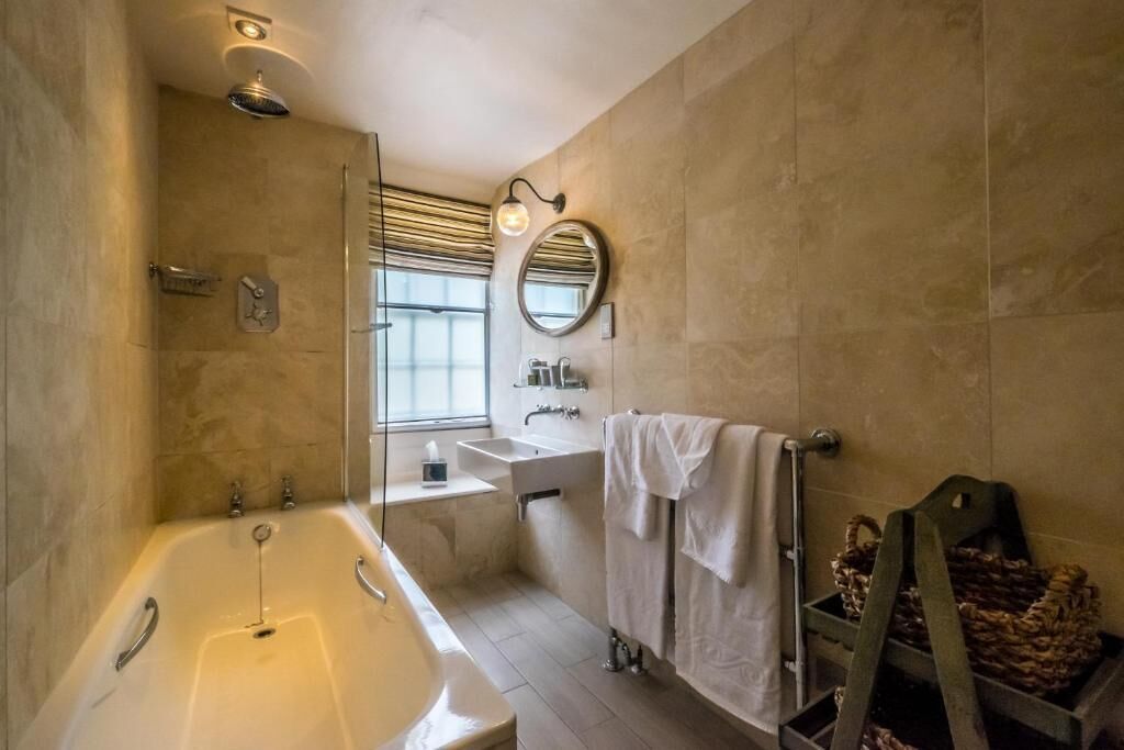 Ein modernes Badezimmer mit Badewanne, Waschbecken, Spiegel und Fenster.