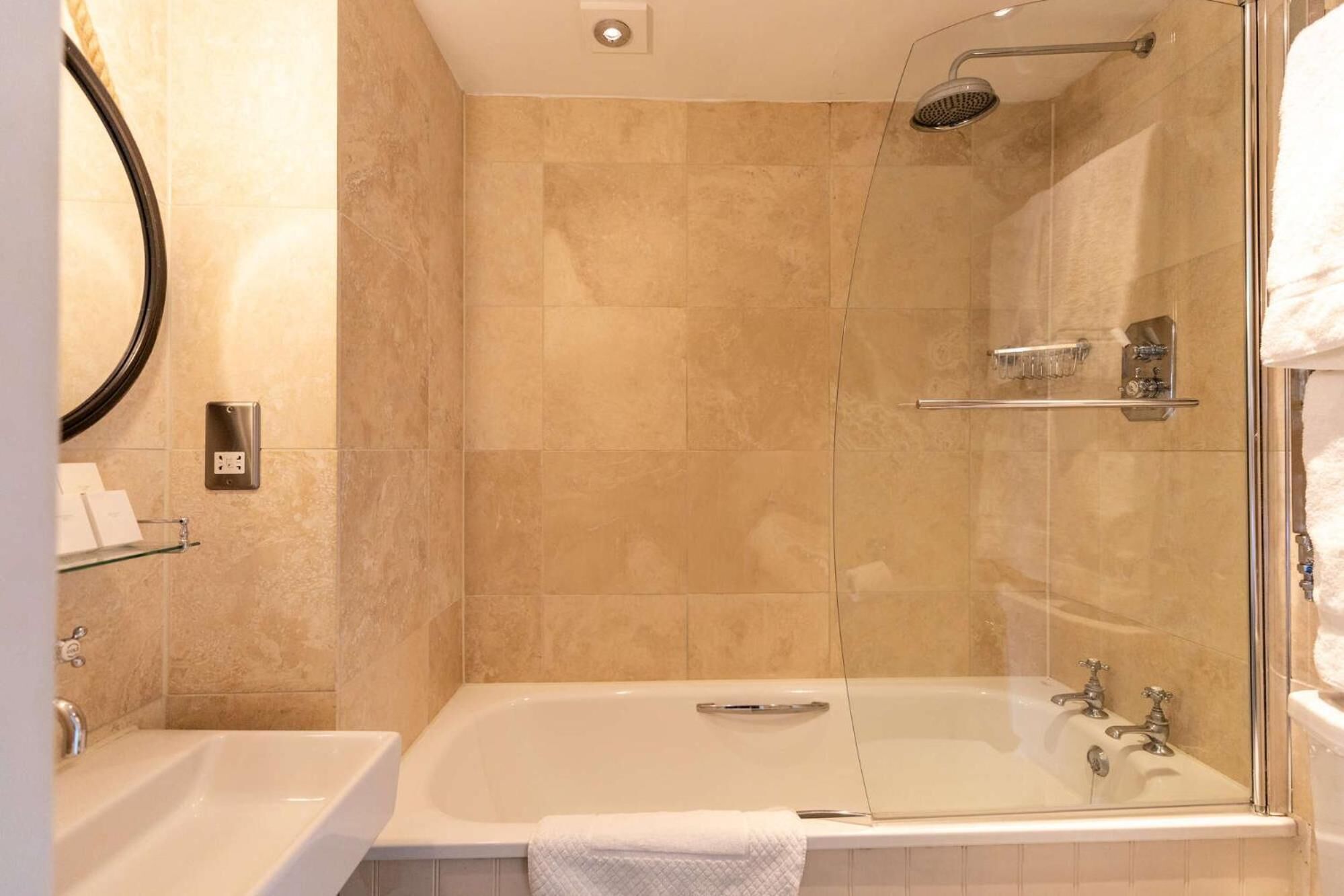 A bathroom with a glass-enclosed shower, a bathtub, and a sink.