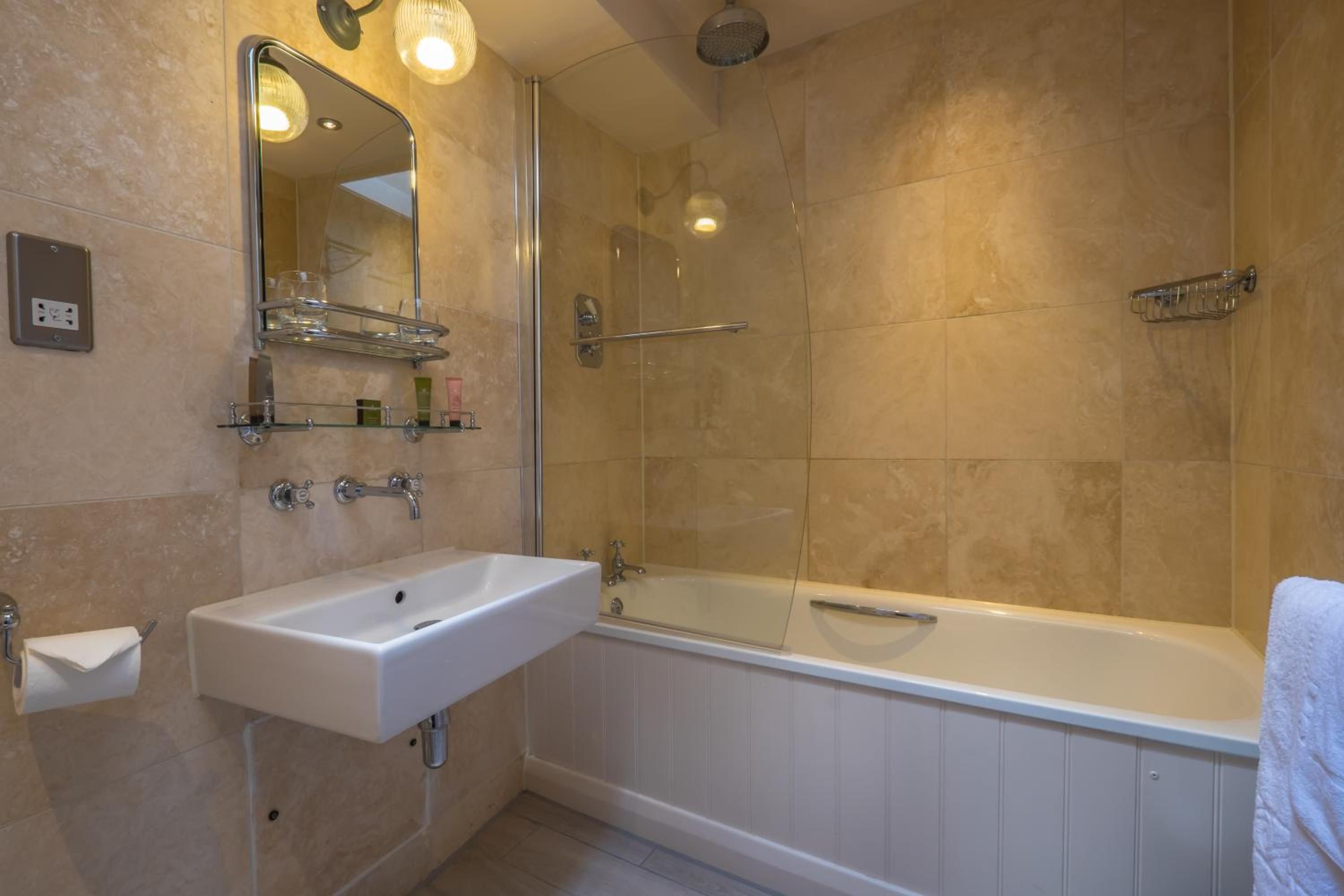 Un baño con lavamanos blanco, espejo, ducha y bañera.
