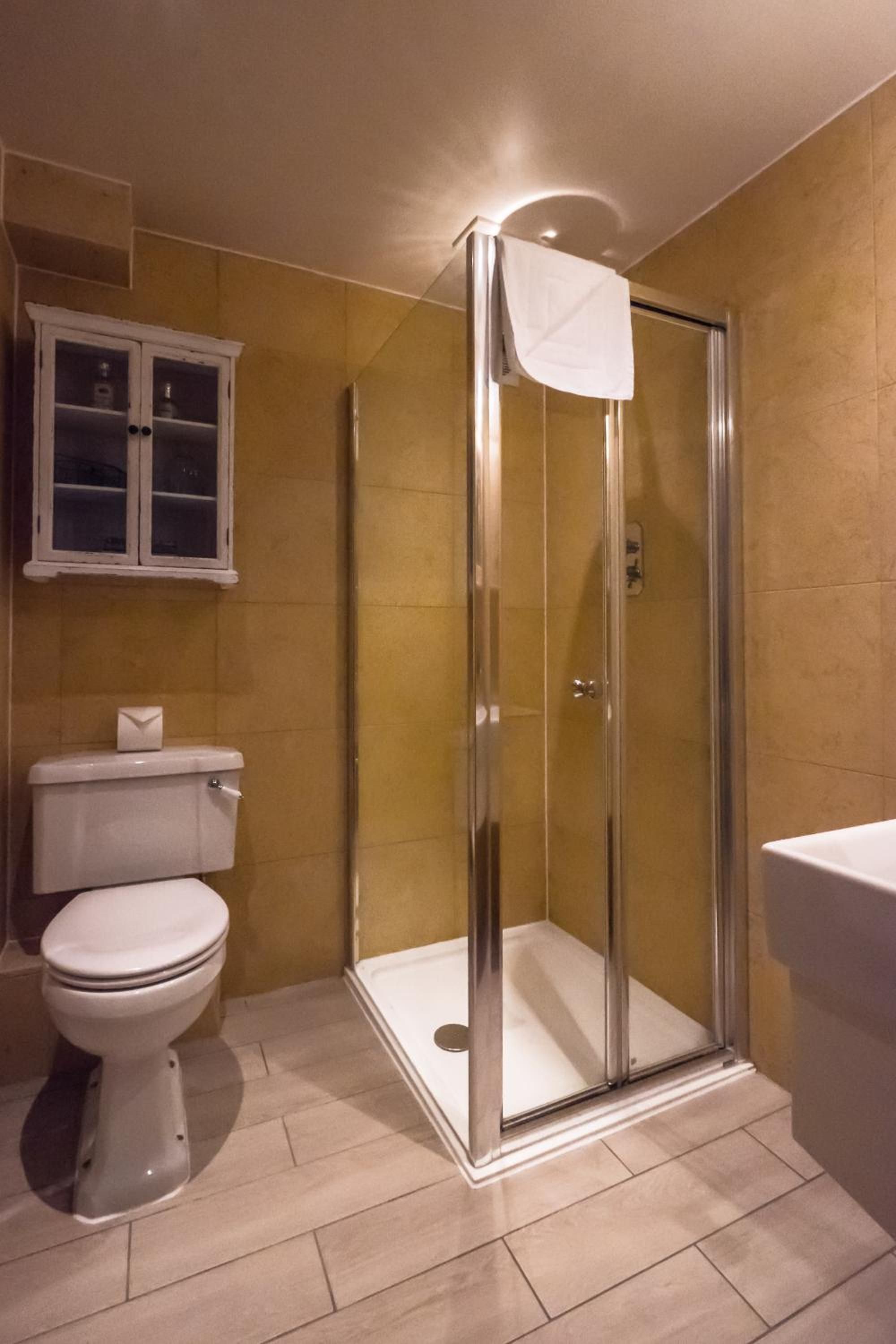 Ein Badezimmer mit einer gläsernen Duschkabine, einer Toilette und einem Schrank mit Glastüren.