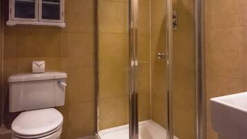 Ein Badezimmer mit einer gläsernen Duschkabine, einer Toilette und einem Schrank mit Glastüren.
