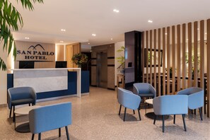 A reception area with a reception desk, seating, and a plant. - San Pablo Hotel (Bogotá)