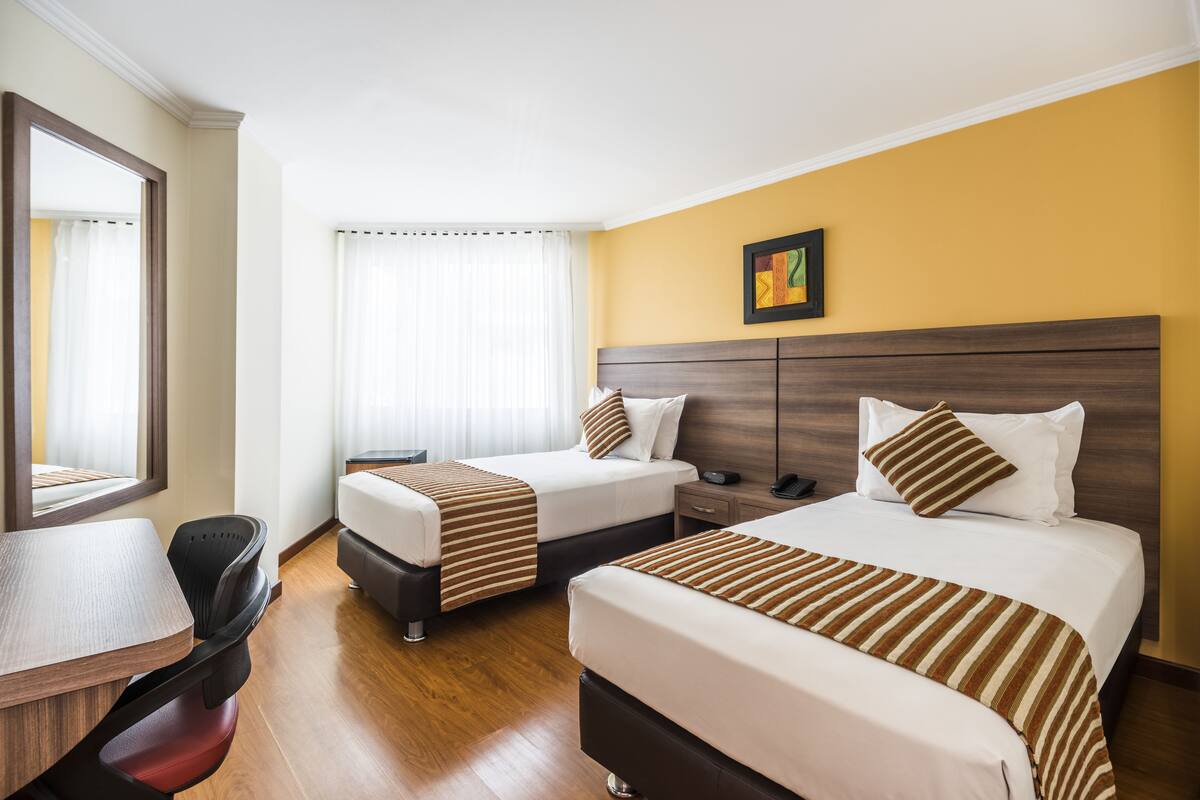 Una habitación de hotel con dos camas, un escritorio y una silla.