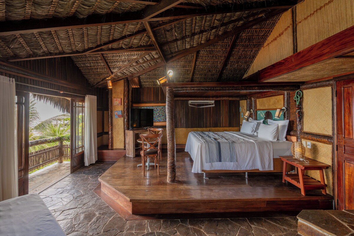 A spacious bedroom with a large bed, a wooden desk, and a television.