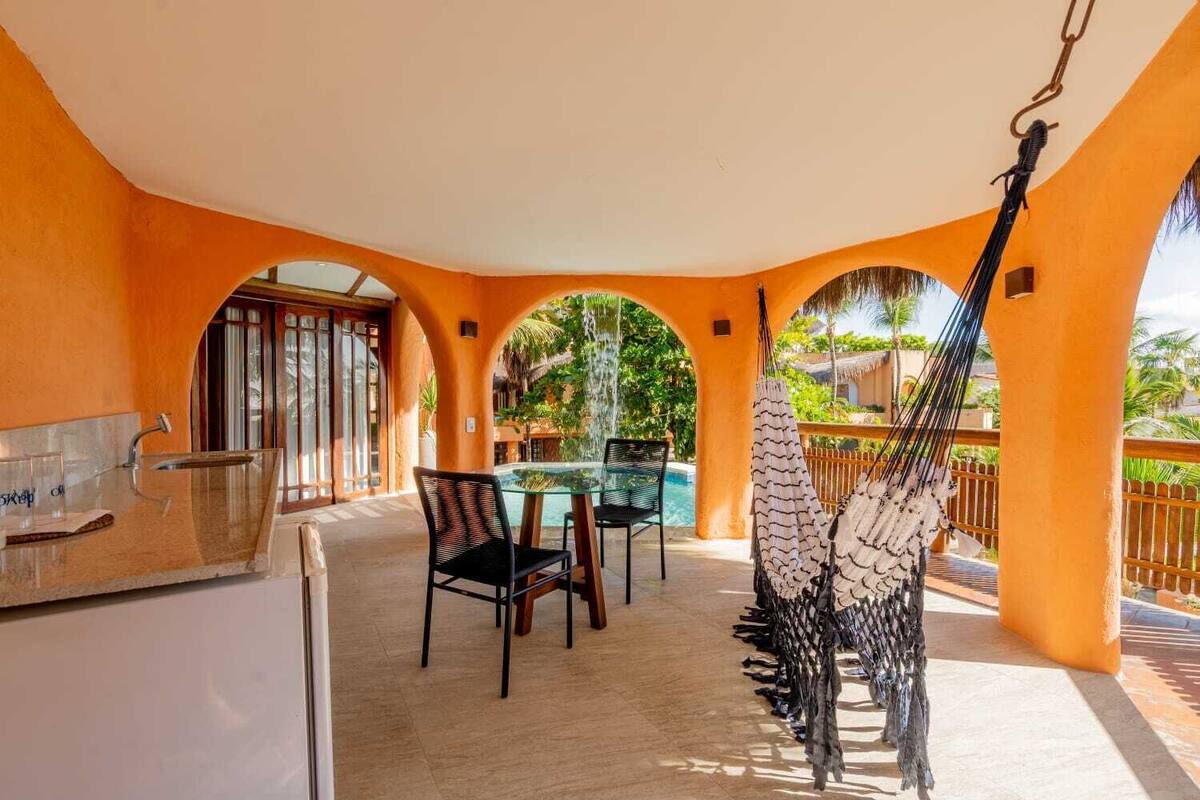 A covered outdoor area with a pool, seating, and a hammock.