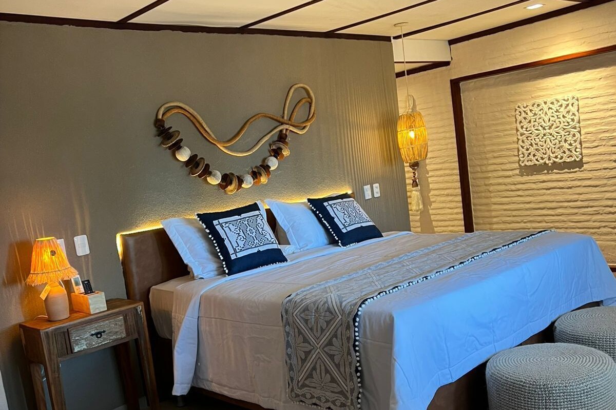 A bedroom with a bed, bedside tables, a lamp, and a decorative wall piece.