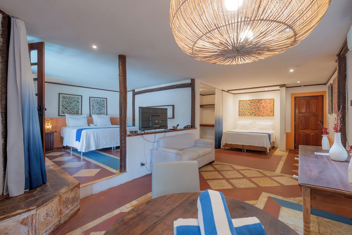 A hotel room with a bed, a sofa, a TV, and a dining area.