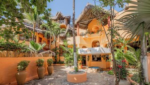 A courtyard with thatched-roof buildings, potted plants, and a stone-paved area. - Dayo Hotel (Trairi)