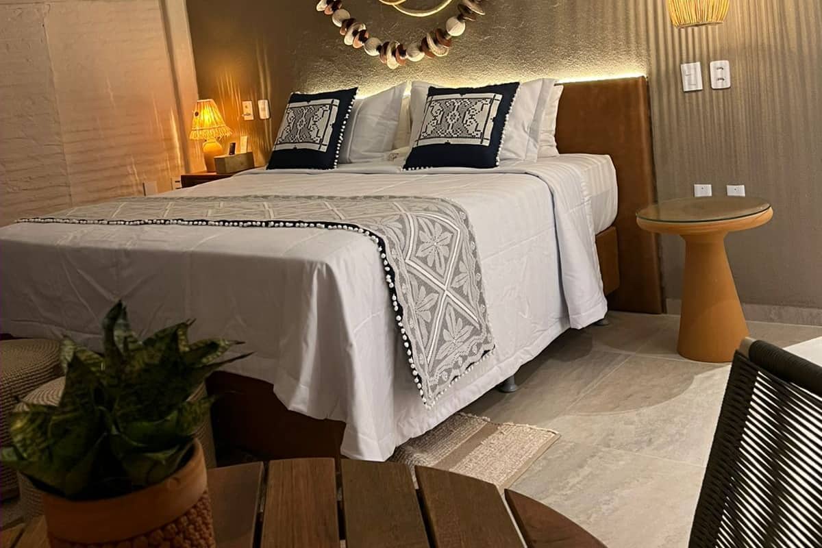 A modern bedroom with a bed, bedside lamps, a hanging light fixture, and a small round table.