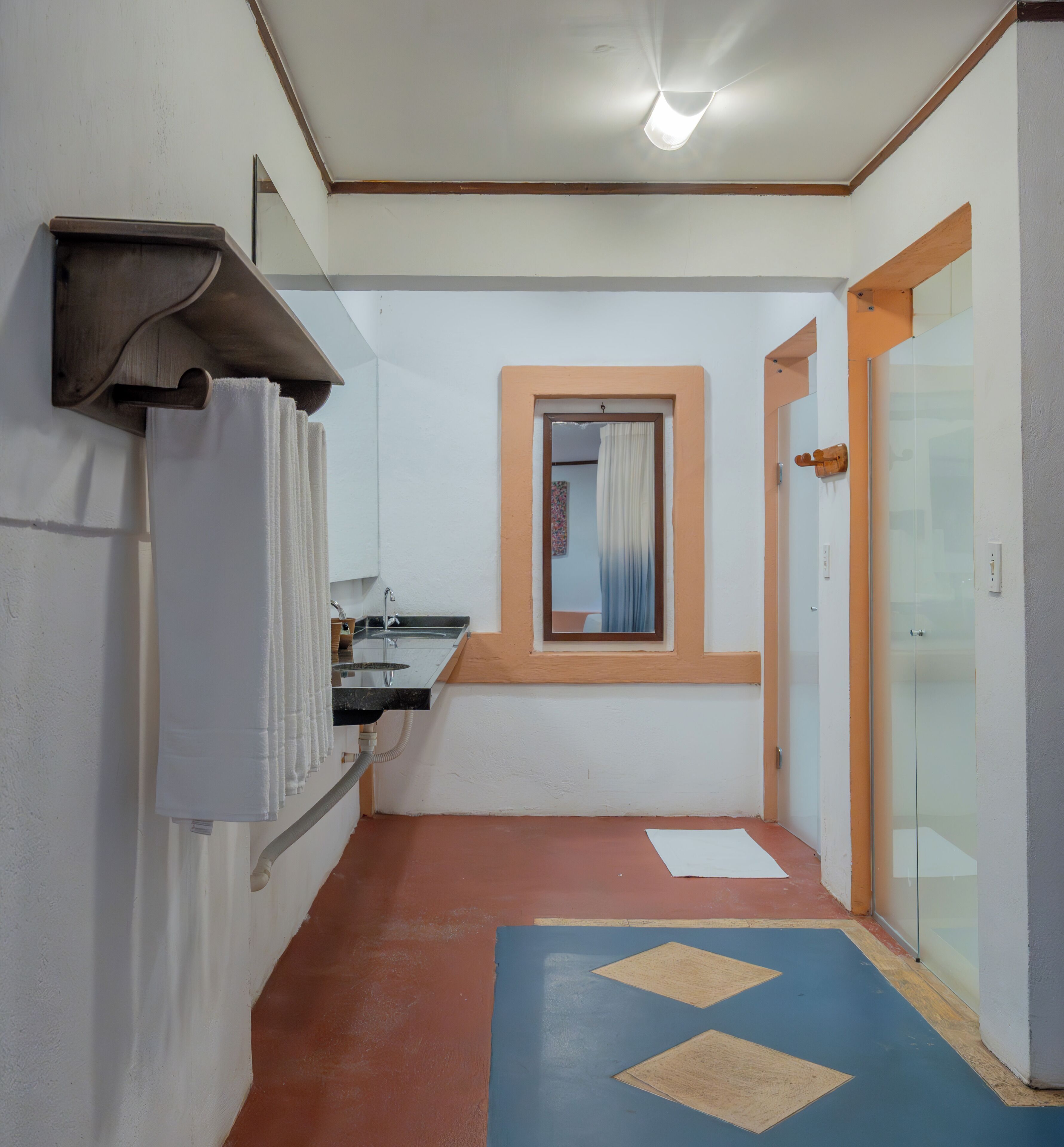 Un couloir étroit avec un lavabo, un miroir et une porte donnant sur une autre pièce.