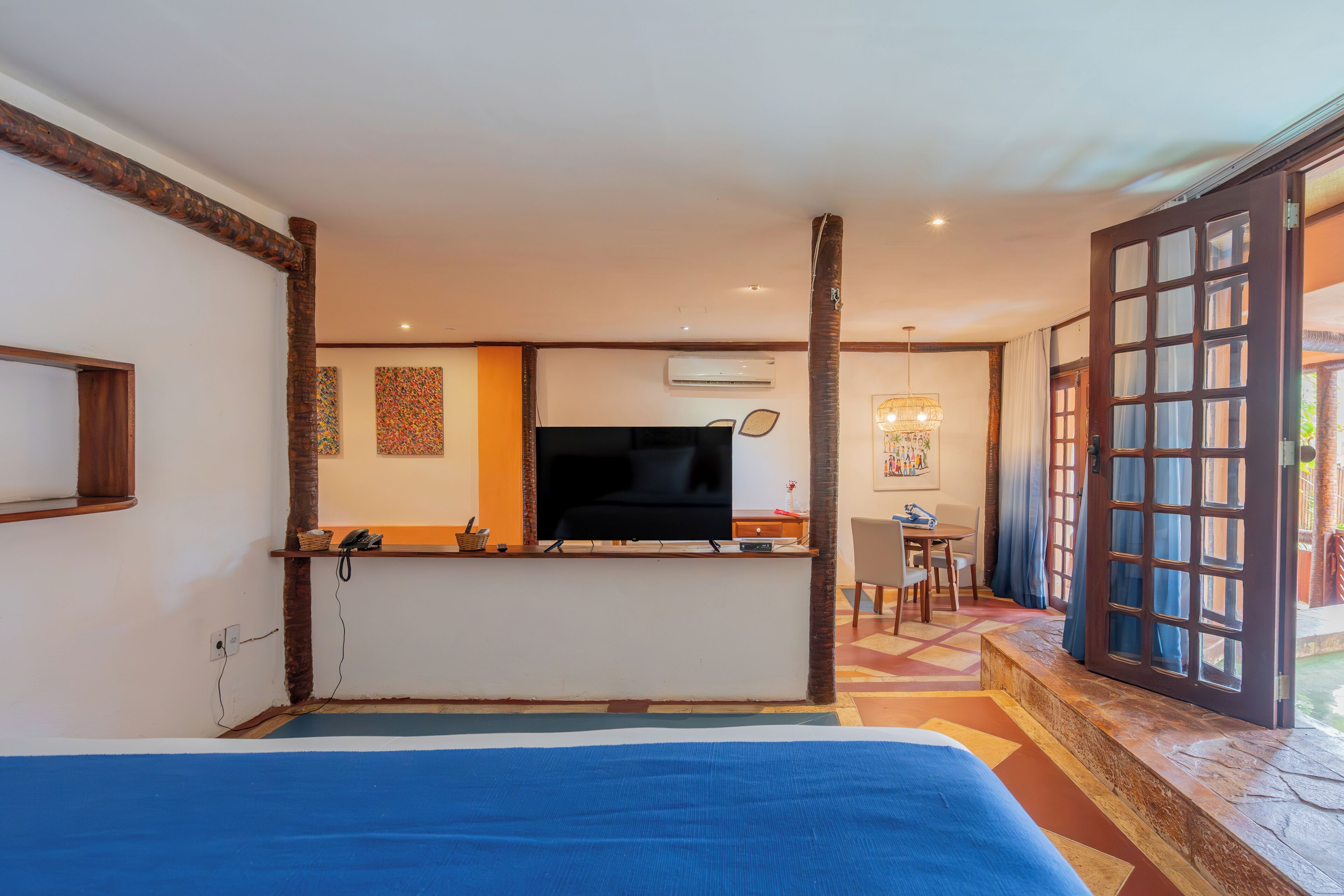 Une chambre d’hôtel avec un lit, un bureau avec une télévision, une chaise et une vue sur l’extérieur.
