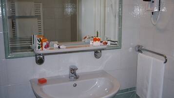 A bathroom with a sink, mirror, towel rack, and a hairdryer mounted on the wall.
